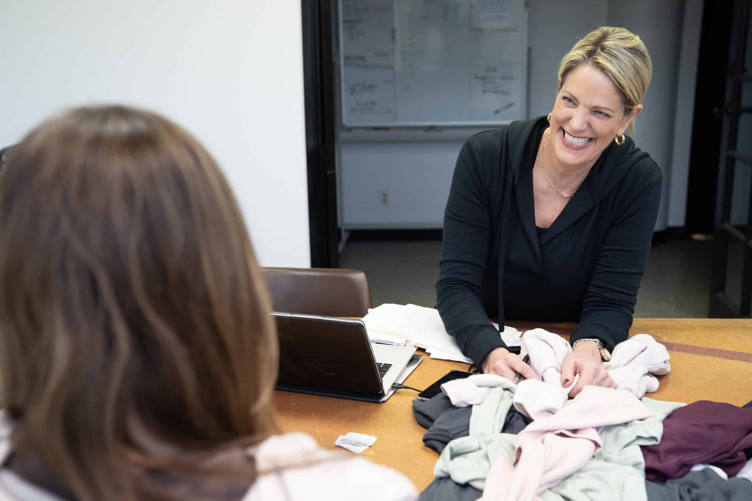 Kirsten K. Harris reviewing product and material decisions during a working apparel meeting.